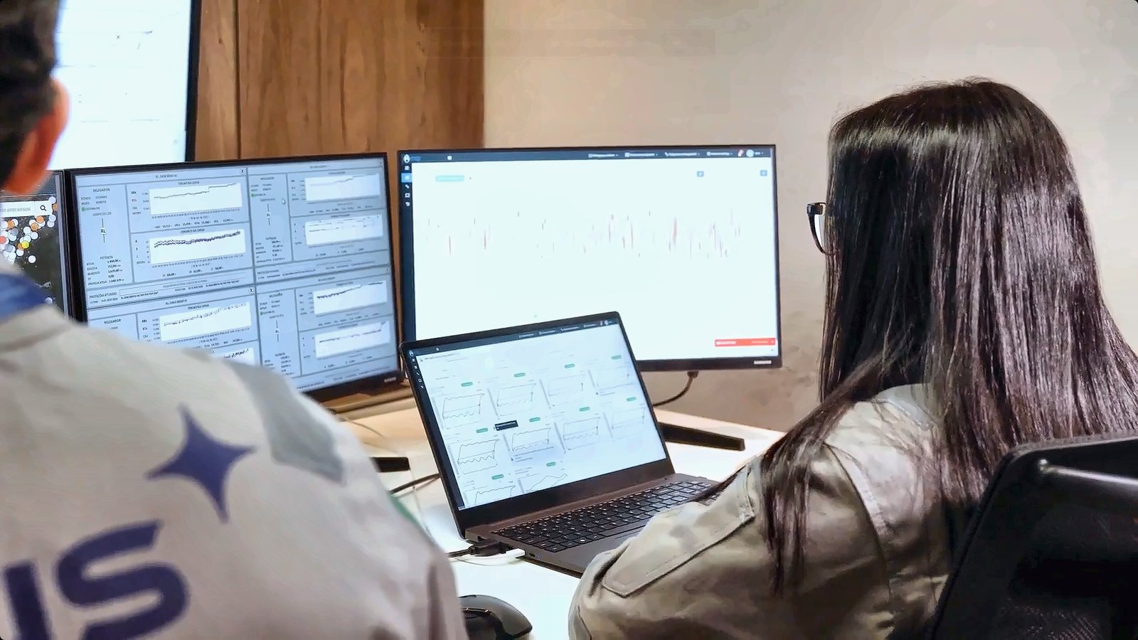 Analista da IDUS acompanhando gráficos de processo em monitores e notebook